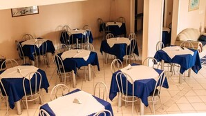 A dining area with multiple tables and chairs, arranged in a spacious room with a tiled floor.