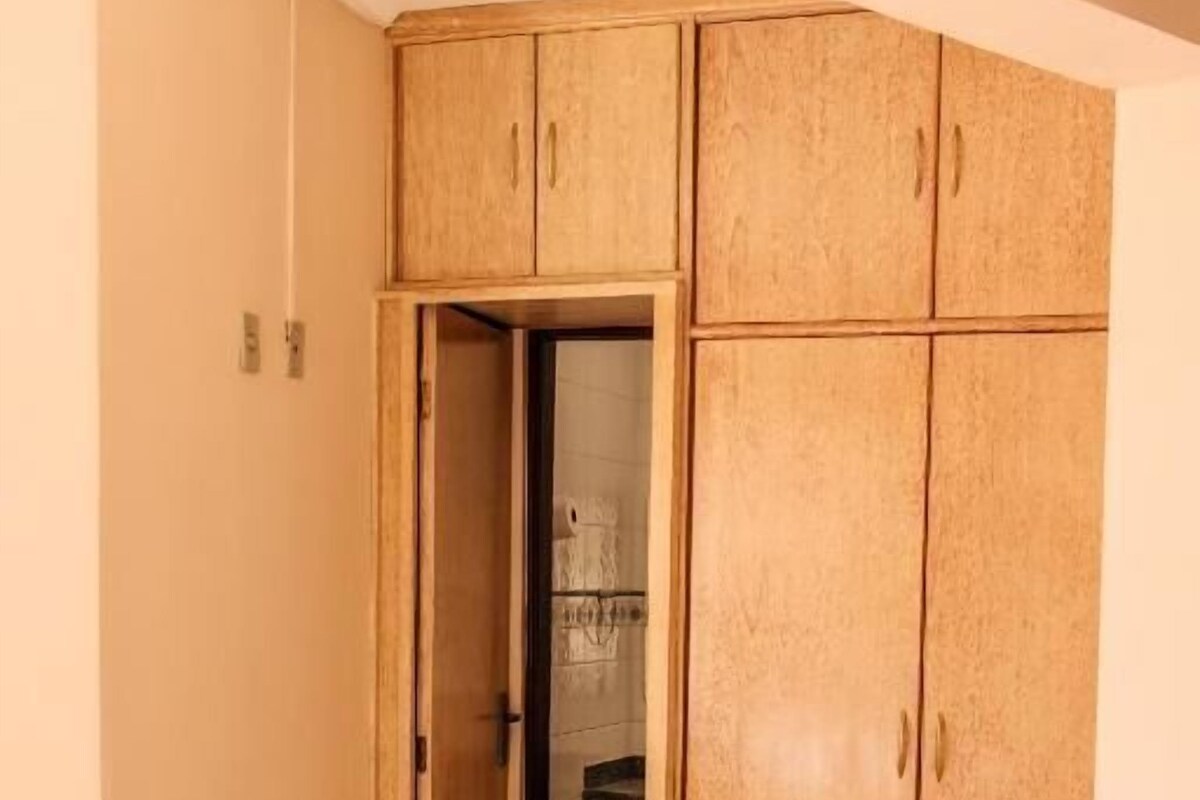 A bedroom with a bed, a wardrobe, and a door leading to a bathroom.