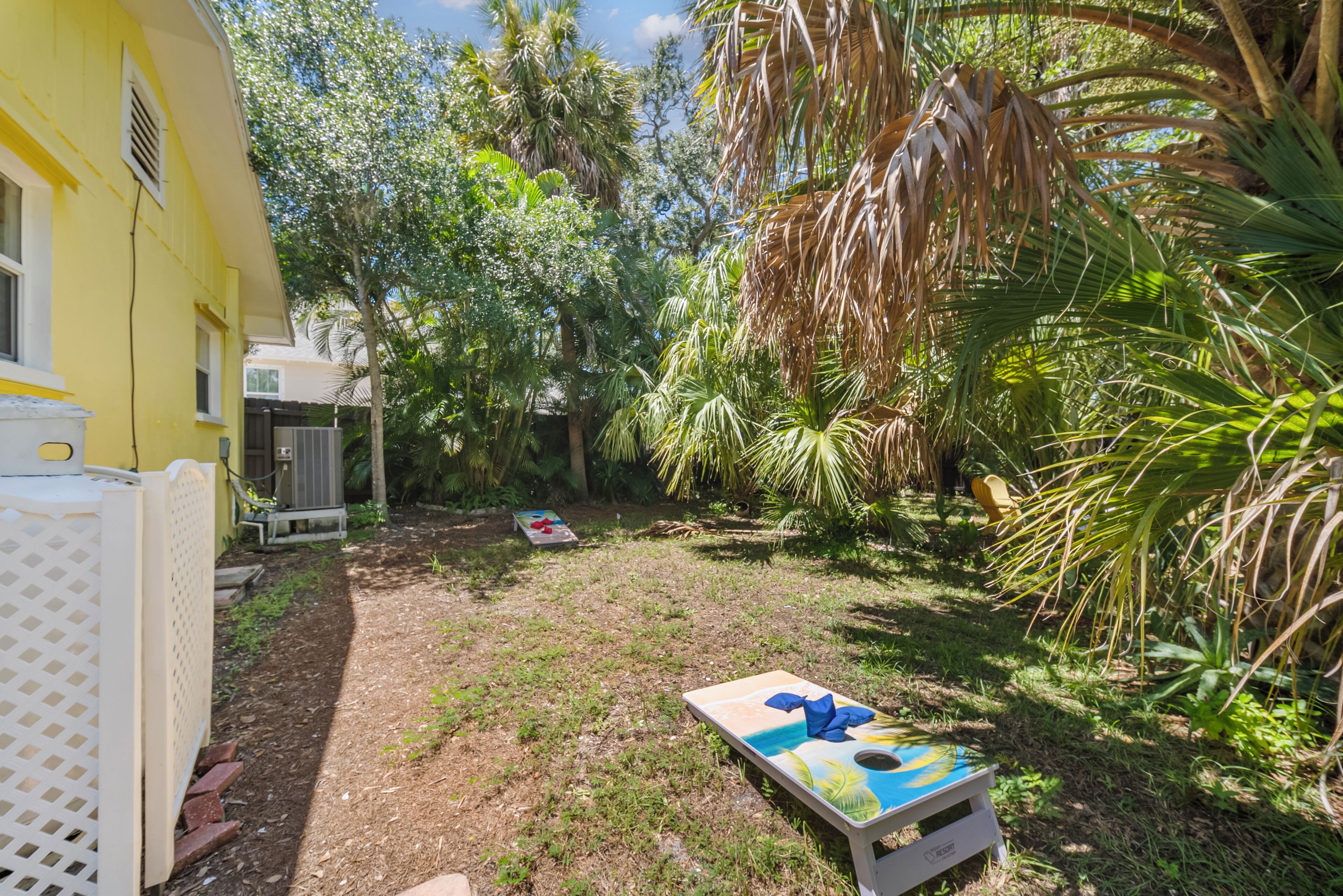 A backyard with a pool table, a yellow building, and lush greenery.