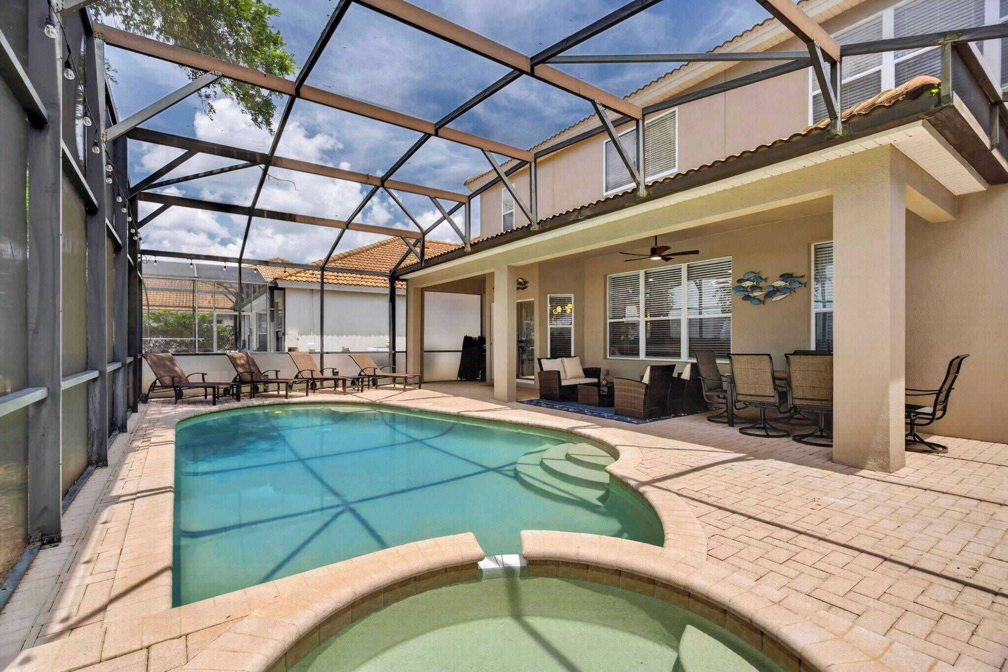 An indoor swimming pool with a glass ceiling, lounge chairs, and a patio area with seating.
