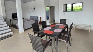 Un amplio salón con una mesa de comedor, sillas, un sofá y una televisión.