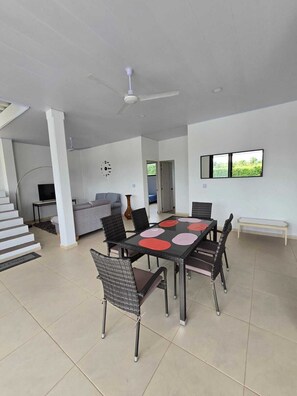 A spacious living area with a dining table, chairs, a sofa, and a television.