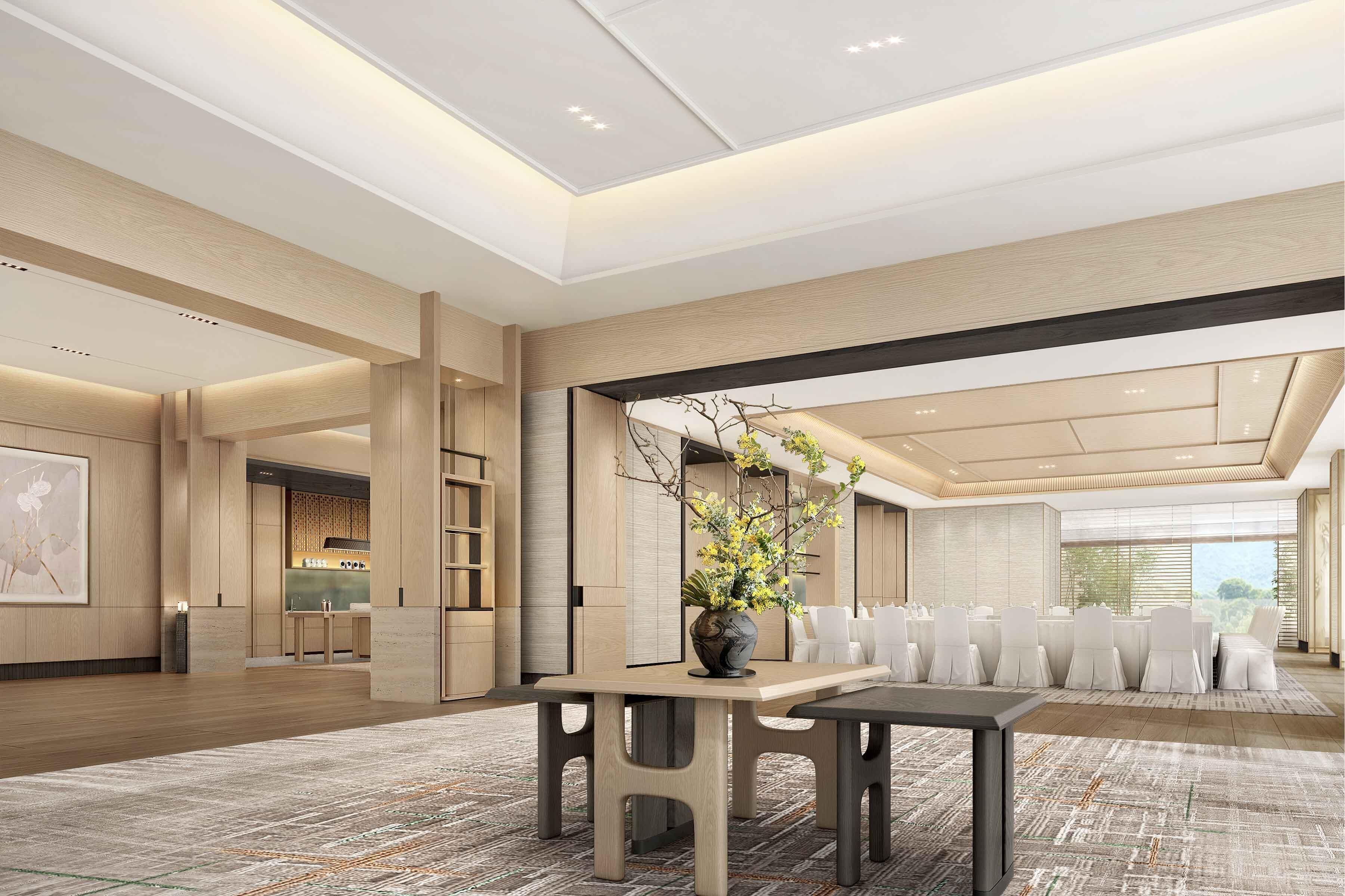 Un amplio vestíbulo de hotel con una recepción, un área de comedor con mesa y sillas, y un ventanal que ofrece vistas.