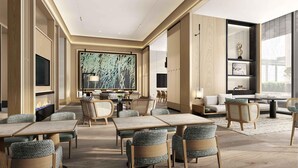 Un moderno vestíbulo de hotel con un cuadro abstracto de gran tamaño, asientos cómodos y un amplio ventanal con vistas.