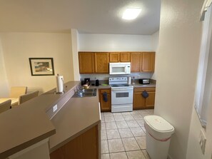 A compact kitchen with wooden cabinets, a microwave, an oven, and a sink. - Stunning 3 Beds Newly Townhouse (Kissimmee)
