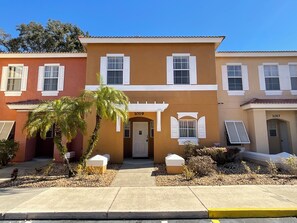 A row of townhouses with a central entrance, numbered 1019 and 1017, and a palm tree in the foreground. - Stunning 3 Beds Newly Townhouse (Kissimmee)