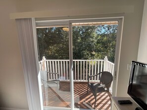 A room with a sliding glass door leading to an outdoor deck with a white railing and two chairs. - Stunning 3 Beds Newly Townhouse (Kissimmee)