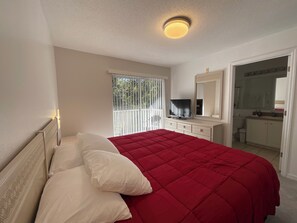 A bedroom with a bed, a television, a mirror, and a bathroom visible through an open door. - Stunning 3 Beds Newly Townhouse (Kissimmee)