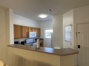 A kitchen with wooden cabinets, a microwave, an oven, and a refrigerator. - Stunning 3 Beds Newly Townhouse (Kissimmee)