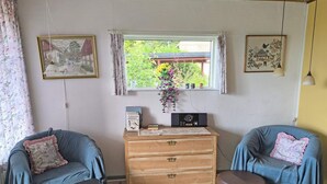 A cozy room with two blue armchairs, a wooden dresser, and a window with a view of greenery. - 6 Person Holiday Home in Nykobing M (Nykobing Mors)
