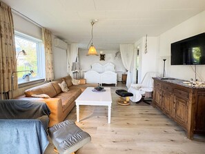 Una sala de estar con un sofá, una mesa de centro, un televisor y un armario de madera.
