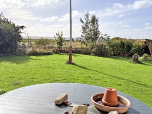 Un espacio de estar al aire libre, circular, con una mesa, una maceta de terracota y piedra.