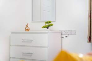 A white dresser with drawers, a small potted plant, and a decorative item on top. - Modern 5 Bed Flat in Thornaby Road For Big Groups (Stockton-on-Tees)