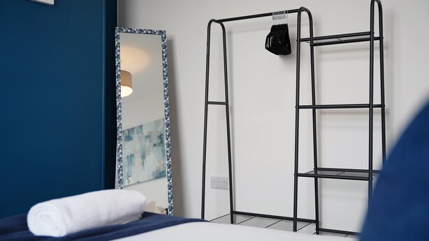 Una habitación de hotel con una cama, un estante en la pared y un espejo.