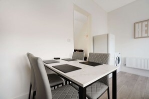 Un espace repas moderne avec une table en marbre, des chaises rembourrées et un four encastré.