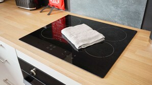 Cocina con tope de inducción negro y extractor de acero inoxidable.