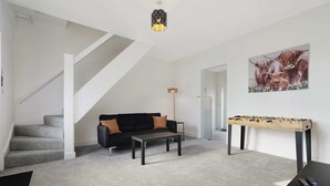 Una sala de estar moderna con un sofá, una mesa de centro y una mesa de futbolín.