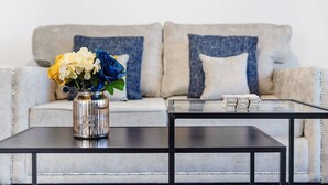 A living room with a sofa, a coffee table, and a vase with flowers. - Newly Refurbished Near the Coast Sleeps 5 (Newbiggin-by-the-Sea)