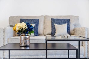 Ein Wohnzimmer mit einer Couch, einem Couchtisch und einer Vase mit Blumen.