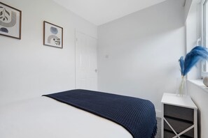 A bedroom with a bed, a bedside table, a window, and two framed artworks on the wall. - 3BR in County Durham With Wifi and Street Parking (Durham)