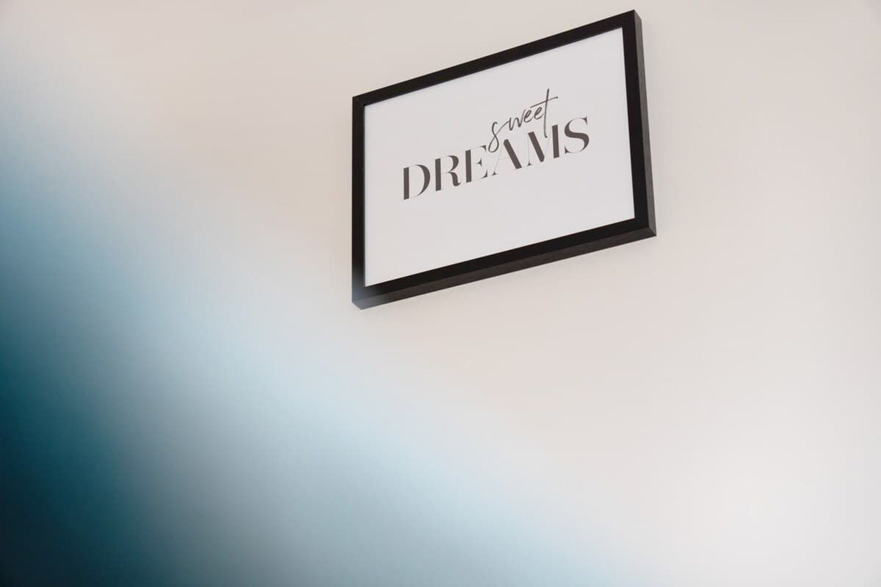 A framed sign with the text 'sweet DREAMS' on a wall.