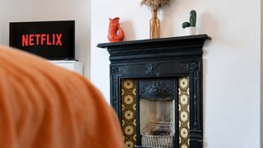 A fireplace with decorative tiles, a vase with dried plants, and a cactus on a mantel. - 2BR Darlington Home by Stay With Us (Darlington)