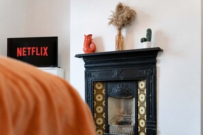 A fireplace with decorative tiles, a vase with dried plants, and a cactus on a mantel. - 2BR Darlington Home by Stay With Us (Darlington)