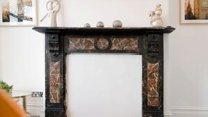 A fireplace with a marble surround, a white door, and decorative items on top. - 2BR Darlington Home by Stay With Us (Darlington)