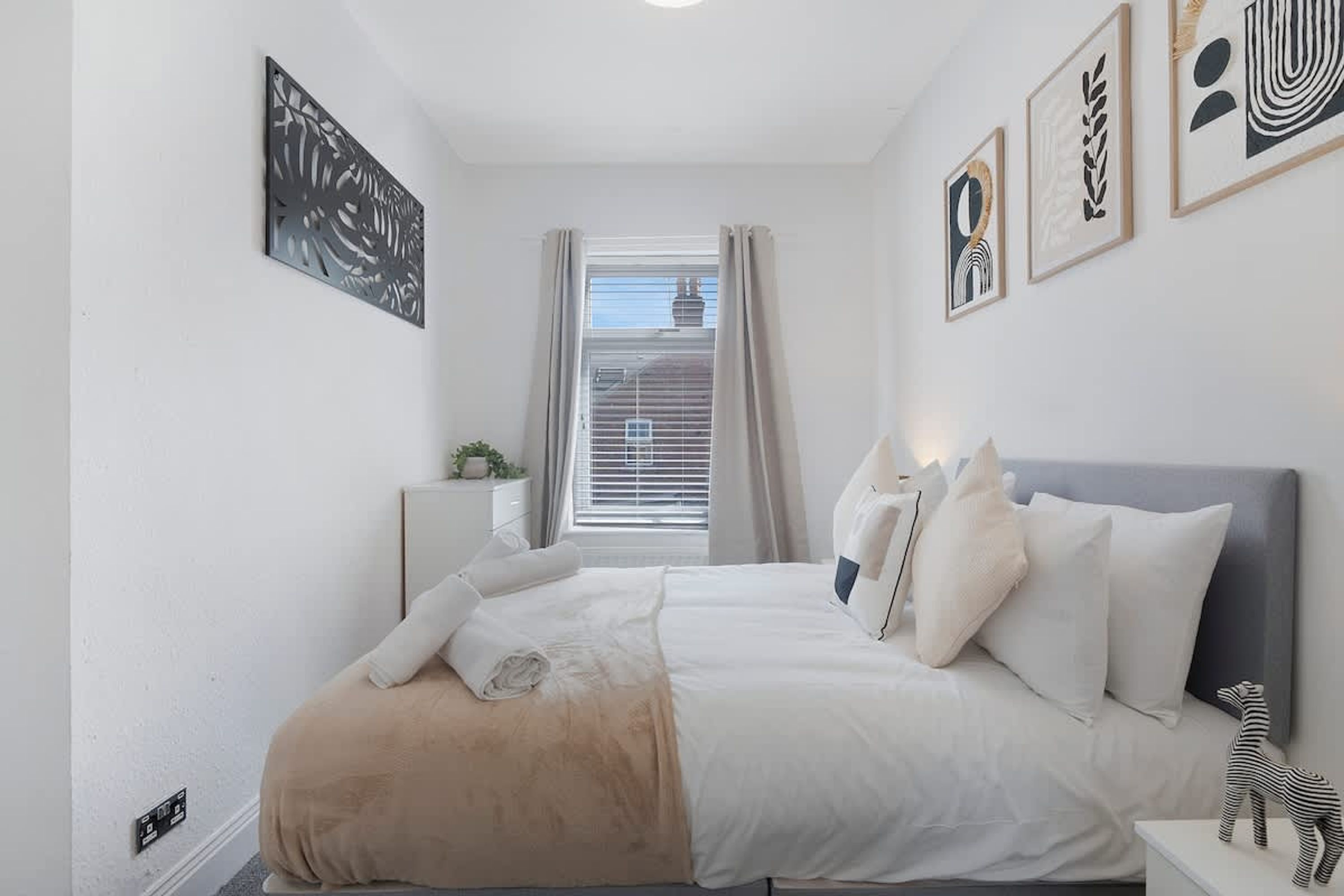 A bedroom with a bed, pillows, a bedside table, and a window with curtains.