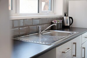 A modern kitchen with a stainless steel sink, a kettle, and a window above the sink. - 2BR Darlington Home by Stay With Us (Darlington)
