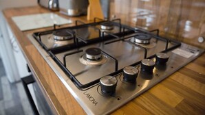 Una cocina con estufa a gas, cuatro hornillas y campana extractora.