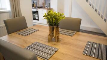 A dining table with four chairs, a central plant, and patterned placemats.