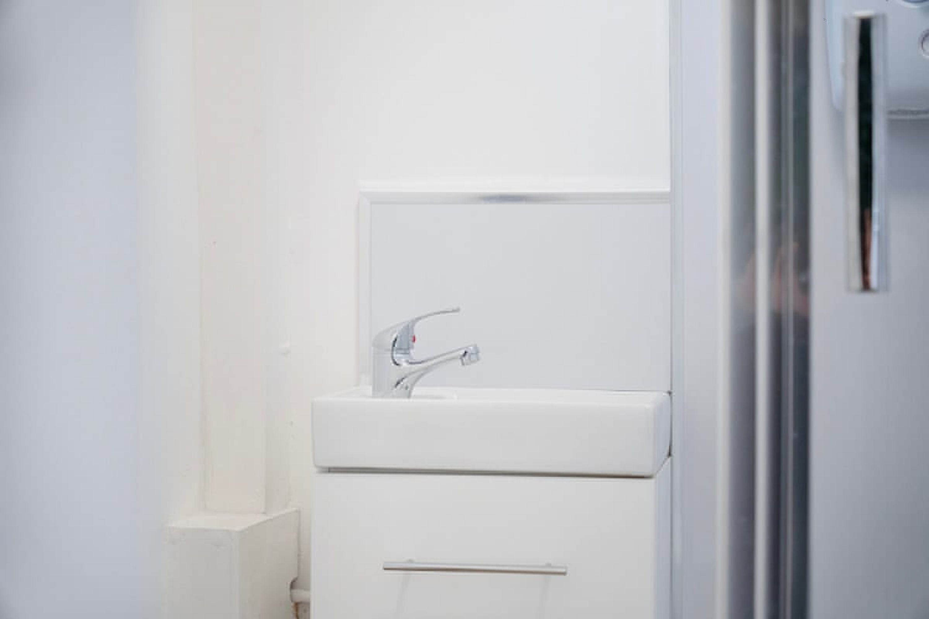 A bathroom with a white sink, a mirror, and a door.