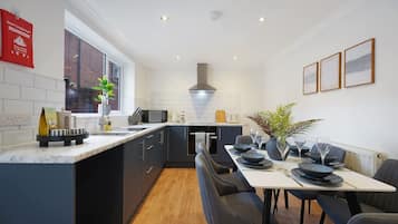 A modern kitchen with a central island, a dining area with a table set for four, and a large window providing natural light.