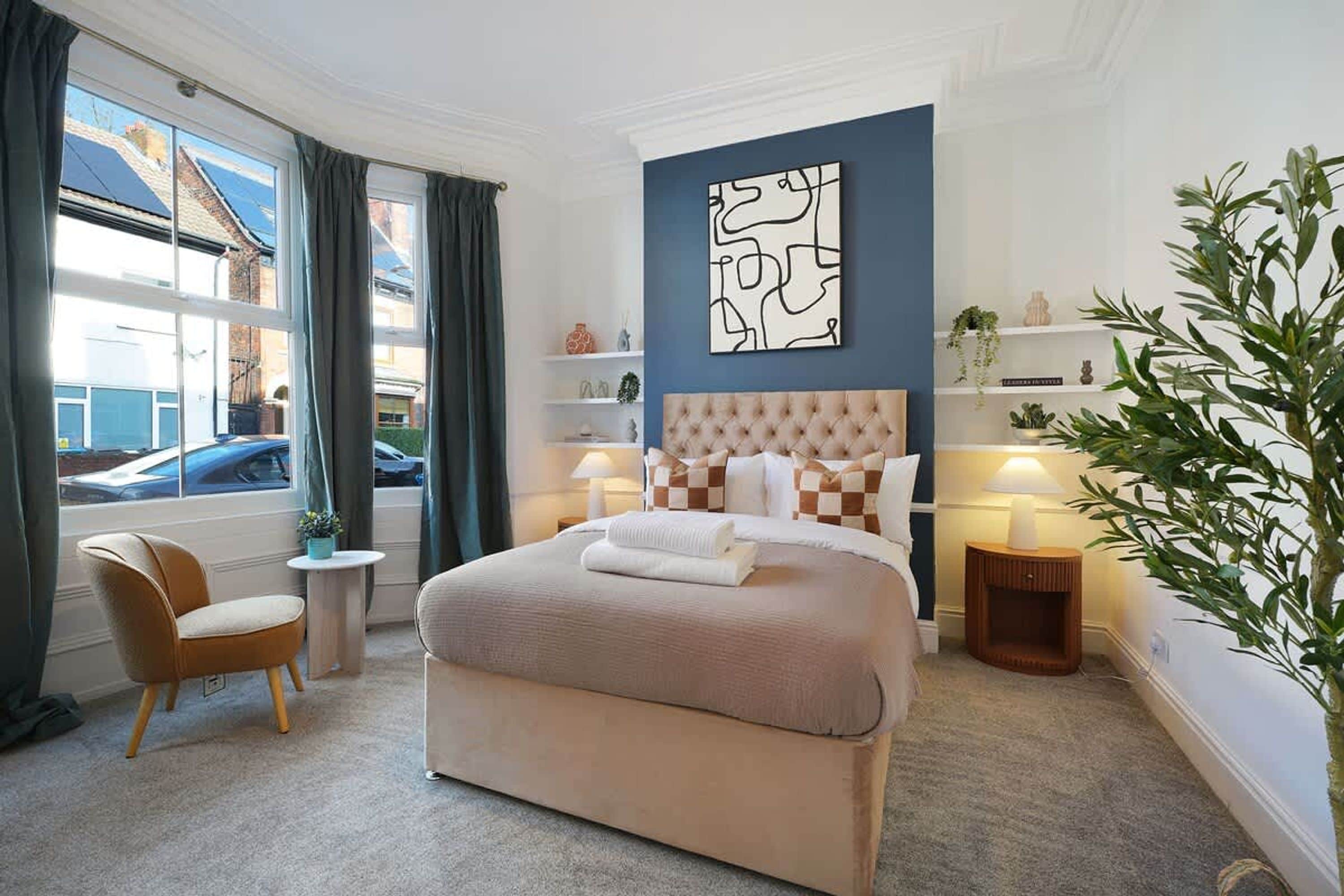 Une chambre d’hôtel avec un grand lit, une chaise, une petite table, une lampe de chevet et une vue sur la rue.
