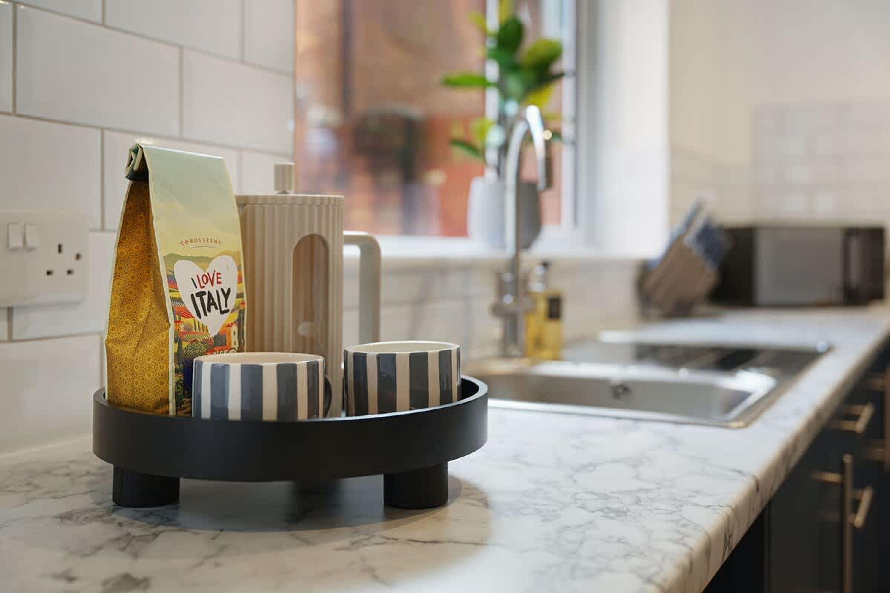 A kitchen counter with a coffee maker, a mug, and a bag of coffee.
