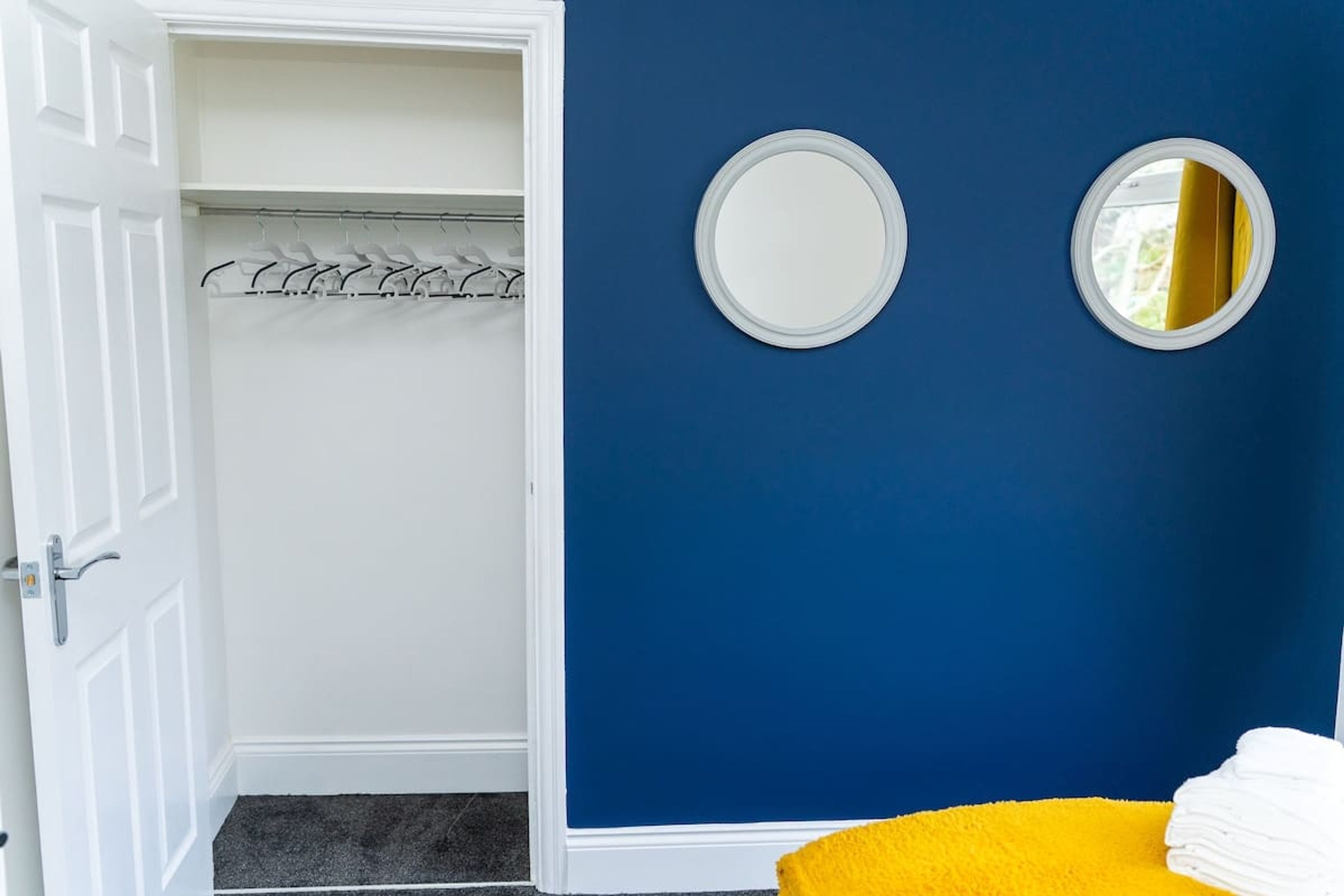 A room with a blue wall, a white door, and a yellow chair.