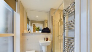 Un baño moderno con inodoro, lavamanos y cabina de ducha de vidrio.