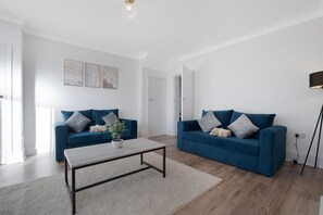 Ein stilvolles Wohnzimmer mit zwei blauen Sofas, einem Couchtisch und einer Stehlampe.