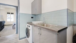Una cocina moderna con lavadora, lavamanos y armario.