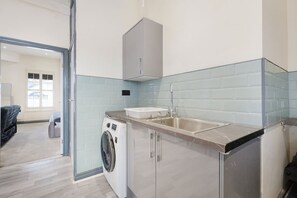 Una cocina moderna con lavadora, lavamanos y armario.
