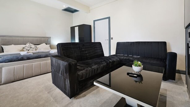Una sala moderna con un sofá, una mesa de centro y una cama con cabecera.