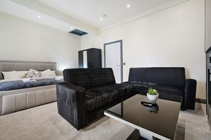 A modern living room with a sofa, a coffee table, and a bed with a headboard. - Modern City Apartment Sleeps 4 by Stay With Us (Bolton)
