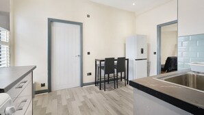 Una cocina moderna con comedor, un refrigerador blanco y un lavamanos de acero inoxidable.