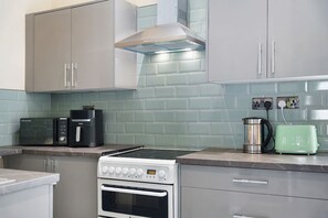 Cocina con estufa, microondas, cafetera y tostadora.