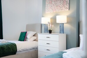 A hotel room with a bed, a bedside table with two lamps, a potted plant, and a wall-mounted artwork. - Relaxing 2BR in Billy Row Wifi by Stay With Us (Crook)