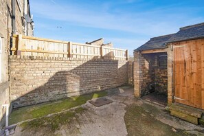 A courtyard with a brick wall, a wooden fence, and a small wooden building. - Relaxing 2BR in Billy Row Wifi by Stay With Us (Crook)