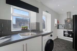 A modern kitchen with a built-in dishwasher, a stainless steel sink, and a black oven. - Relaxing 2BR in Billy Row Wifi by Stay With Us (Crook)