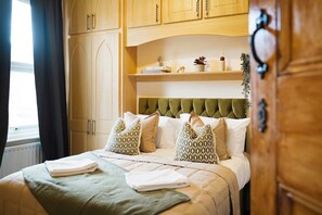 Ein Hotelzimmer mit einem Bett, einem Vorhangfenster, Holzschränken und einem Regal mit Dekoration.