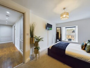 Un dormitorio con cama, televisor, ventana con vistas y una planta.